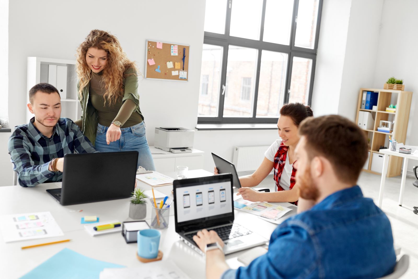 Work office with people sat around a desk on their laptops