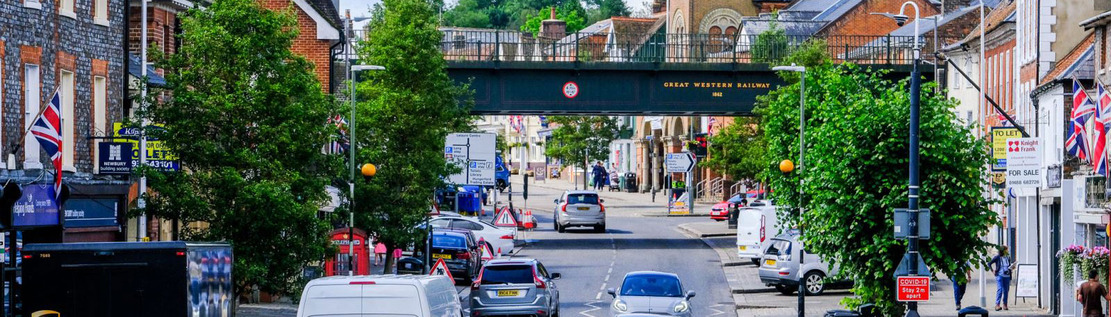 High street looking towards a large black metal railway bridge