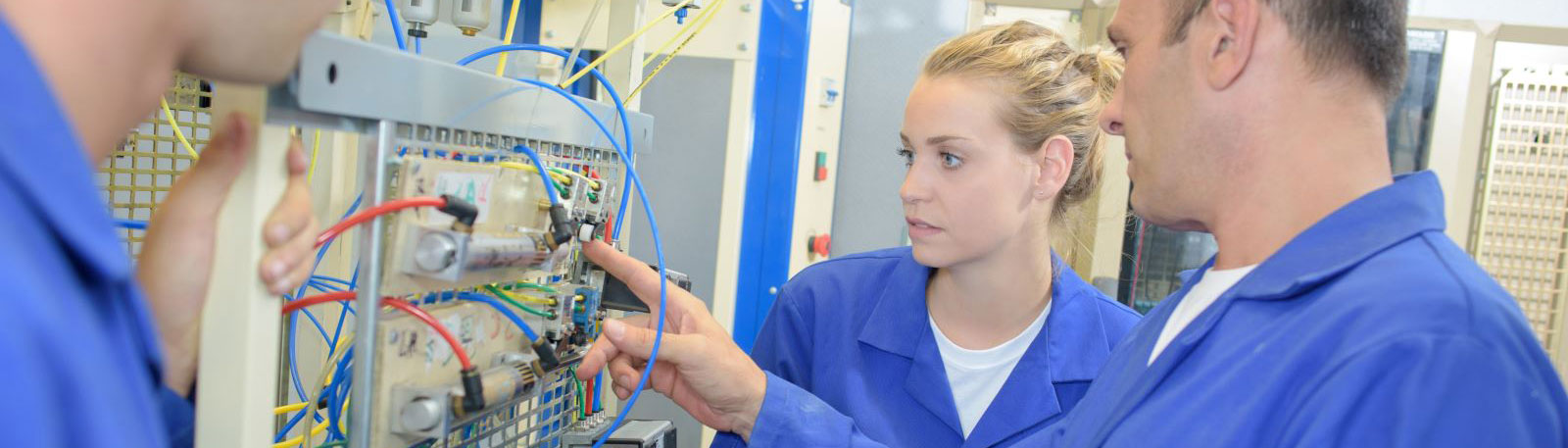 A man and woman in blue overalls studying wiring