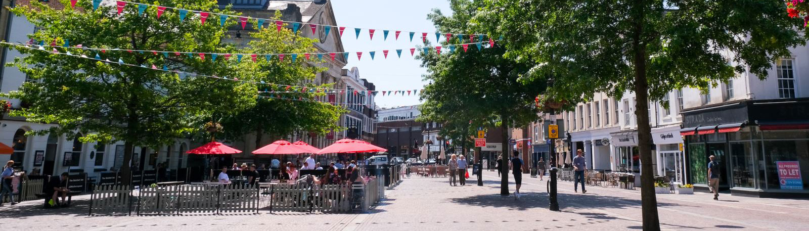 High street with bunting hanging from the trees and lots of people